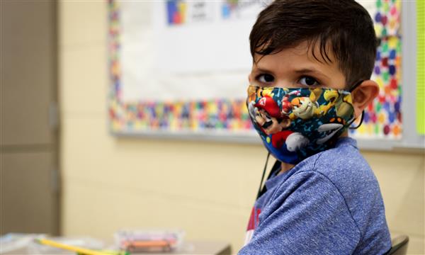 boy smiles while wearing mask